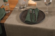 Galda klājums ar smilškrāsas galda celiņu un zaļu salveti.